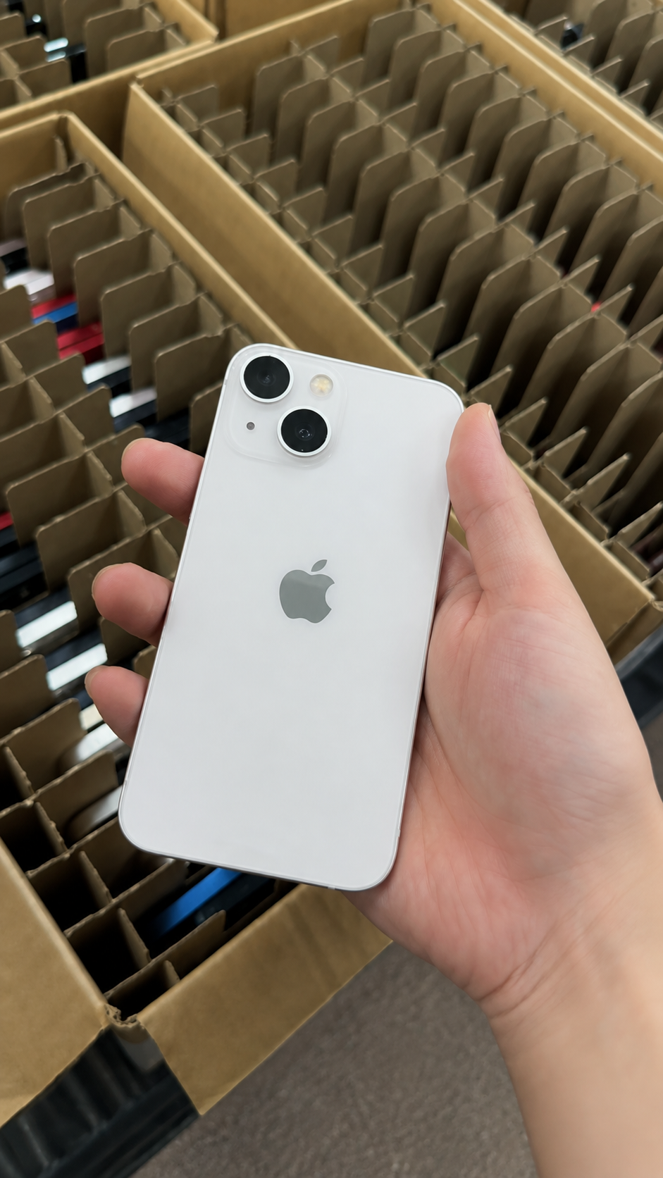 Quality-control technician testing a visually clean used iPhone for display, camera, charging, audio, and connectivity functions