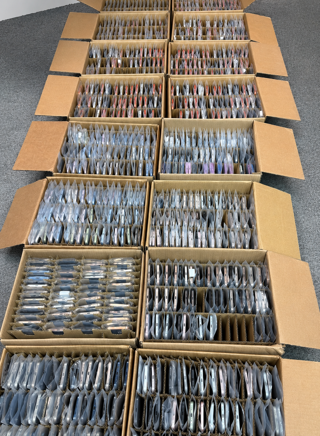 Large wholesale inventory of used iPhones organized in protective cartons for HQB sourcing